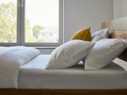 Close-up of luxury white cotton bedding set with duvet cover and pillows on wooden bed, showcasing premium breathable bedding for modern bedrooms.