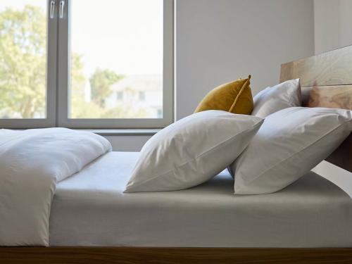 Close-up of luxury white cotton bedding set with duvet cover and pillows on wooden bed, showcasing premium breathable bedding for modern bedrooms.