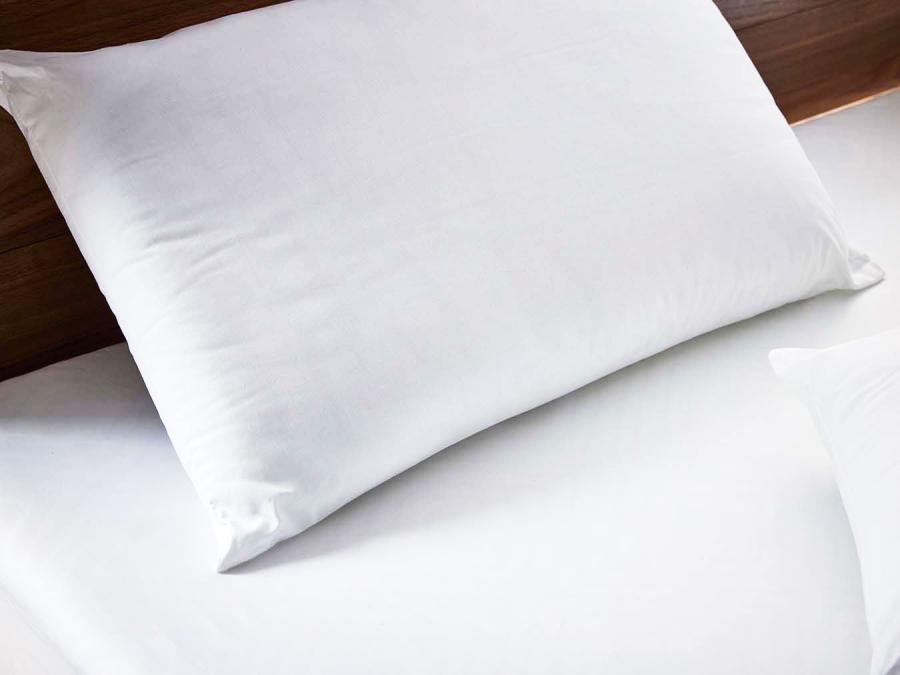 Hollowfiber pillow against a solid walnut wood headboard