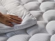 Hand pressing on soft mattress topper