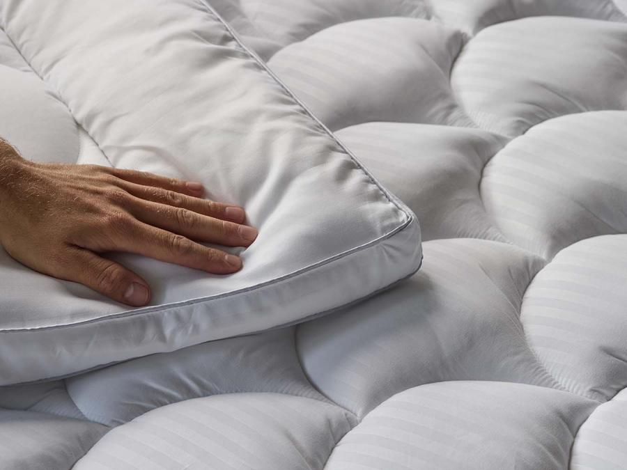 Hand pressing on soft mattress topper